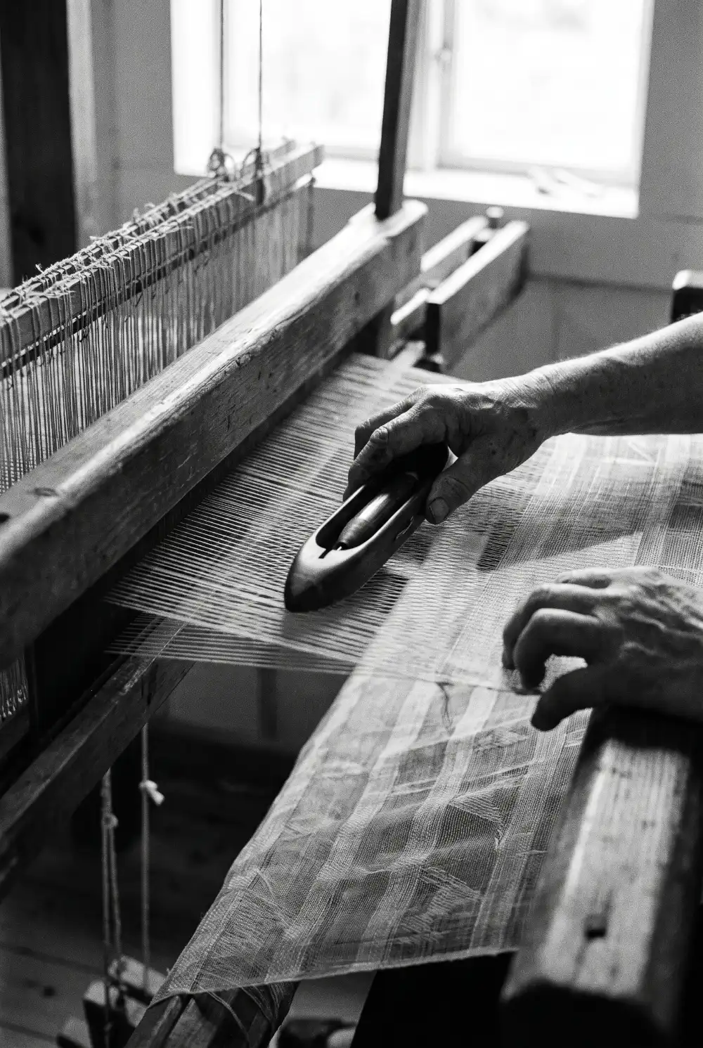 A weaver's hands at the loom, in black and white